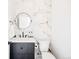 Stylish powder room boasts marble accent wall, round mirror, and modern black fixtures at 2625 W 23Rd Ave, Denver, CO 80211