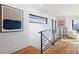 Hallway with hardwood floors, black railing, and artwork, leading to a well-lit sitting area at 2625 W 23Rd Ave, Denver, CO 80211
