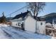 White house with blue accents and snowy landscape at 319 13Th Ave, Idaho Springs, CO 80452