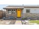 Ranch style home with yellow door, stone facade, and small front yard at 6000 Krameria St, Commerce City, CO 80022