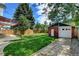 Large backyard with a patio area, grassy lawn, garden, brick garage, and a fenced perimeter at 2636 N Glencoe St, Denver, CO 80207
