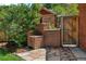 Outdoor brick grill area in a backyard setting with stone pathway and wooden gate access at 2636 N Glencoe St, Denver, CO 80207