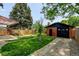 Backyard with green grass, a detached brick garage, and mature trees with a privacy fence at 2636 N Glencoe St, Denver, CO 80207