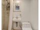 Compact bathroom featuring a pedestal sink, toilet, and walk-in shower with beige tile surround at 2636 N Glencoe St, Denver, CO 80207