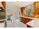 Well-lit kitchen with stainless steel appliances, wood cabinets, white countertops, and a doorway to a staircase at 2636 N Glencoe St, Denver, CO 80207