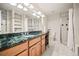Bathroom featuring tiled walk-in shower, storage shelves and vanity with bright, decorative lighting at 36412 Paradise Cir, Elizabeth, CO 80107