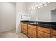 Bathroom featuring a wood vanity with black granite countertop, undermount sink, and a decorative light fixture at 36412 Paradise Cir, Elizabeth, CO 80107