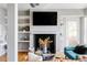 Living room with a fireplace and open shelving above, hardwood flooring, and large windows at 1489 Steele St # 104, Denver, CO 80206