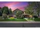 Charming two-story home with lush lawn, mature trees, and professional landscaping at sunset at 5755 S Fulton Way, Greenwood Village, CO 80111