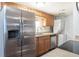 A tidy kitchen features stainless steel appliances, wood cabinets, and in unit laundry area at 13393 E Louisiana Ave, Aurora, CO 80012