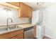 A laundry area features wood cabinets, stainless steel dishwasher, and stackable washer and dryer units at 13393 E Louisiana Ave, Aurora, CO 80012