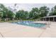 Community pool area featuring a large pool, spacious deck, and manicured green trees in the background at 13393 E Louisiana Ave, Aurora, CO 80012