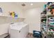 Functional laundry room with a washer, dryer, shelving, and storage for supplies at 935 Peach Leaf Ln, Elizabeth, CO 80107