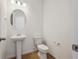 Charming powder room features a pedestal sink, round mirror and a modern toilet at 1331 Rock Cliff Ave, Erie, CO 80516