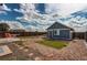 A cozy backyard features a detached garage, a table and chairs on a concrete patio, and artificial turf patches at 55490 E 27Th Pl, Strasburg, CO 80136