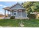 Charming blue home featuring a covered porch, well-maintained lawn, and mature tree at 55490 E 27Th Pl, Strasburg, CO 80136
