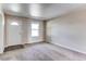 Carpeted living room with a white front door, window, and neutral wall color at 55490 E 27Th Pl, Strasburg, CO 80136