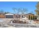 Charming ranch style home featuring a gray garage door, brick accents, and a beautifully landscaped front yard at 5121 W Plymouth Dr, Littleton, CO 80128