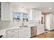 Kitchen with stainless steel dishwasher, sink, white cabinets, and quartz counters at 5121 W Plymouth Dr, Littleton, CO 80128