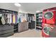 Well-organized laundry room with shelving, cabinets, closet rod and stacked red washer and dryer at 5121 W Plymouth Dr, Littleton, CO 80128