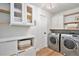 Well-organized laundry room with modern washer and dryer, floating shelves, and cabinet space at 5121 W Plymouth Dr, Littleton, CO 80128