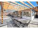 Outdoor dining space under a pergola with string lights, next to the brick and white trimmed house at 5121 W Plymouth Dr, Littleton, CO 80128