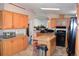 Kitchen featuring an island, wood cabinetry, and modern black appliances at 11299 E 159Th Pl, Brighton, CO 80602