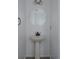 Stylish half bathroom featuring a pedestal sink, round mirror, and modern fixtures at 11538 Hudson St, Thornton, CO 80233