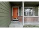 Inviting front porch with an orange door, brick trim, and large window at 11538 Hudson St, Thornton, CO 80233