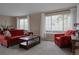 Bright living room with carpet, featuring large windows and red sofa and armchair at 11538 Hudson St, Thornton, CO 80233