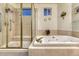 Bathroom featuring a tiled glass shower and a jetted tub with brass fixtures at 7454 Snow Lily Pl, Castle Pines, CO 80108