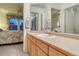 Bathroom vanity with peach counter, gold faucet and large framed mirror, with views of bedroom and closet at 7454 Snow Lily Pl, Castle Pines, CO 80108