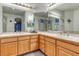 Bathroom featuring double sinks, mirrored walls, wooden cabinets, and a glass shower at 7454 Snow Lily Pl, Castle Pines, CO 80108