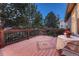 Deck area with wooden flooring, dark metal railings and outdoor table and chairs at 7454 Snow Lily Pl, Castle Pines, CO 80108