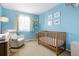 Adorable Bedroom room painted in baby blue, featuring a crib and comfortable chair at 17623 Cornish Pl, Parker, CO 80134