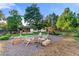 Spacious backyard with outdoor seating area, manicured lawn, mature trees, and a fun playground set at 1920 S Niagara St, Denver, CO 80224