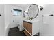 Modern bathroom featuring a round mirror, vanity with storage, and stylish black hexagon tile flooring at 1920 S Niagara St, Denver, CO 80224