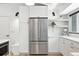 Bright kitchen features stainless steel refrigerator and white cabinets, offering modern appeal and ample storage at 1920 S Niagara St, Denver, CO 80224