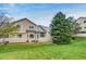 Back of the home featuring a large lawn, mature trees, and patios at 3179 S Indiana St, Lakewood, CO 80228