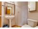 Cozy half bathroom with pedestal sink, toilet and tile flooring at 3179 S Indiana St, Lakewood, CO 80228