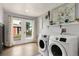 Bright laundry room with modern washer and dryer, white cabinets, shelves, and backyard access at 805 5Th St, Fort Lupton, CO 80621