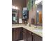 Bathroom featuring dual sinks, granite countertops, dark wood cabinets, and decorative hanging greenery at 17046 Wellington Dr, Parker, CO 80134