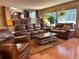Open concept living room with leather furniture, wood floors, and large windows that provide natural light at 17046 Wellington Dr, Parker, CO 80134