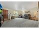Spacious living room featuring plush carpeting, comfortable leather seating, and natural light from the window at 6651 S Dudley Ct, Littleton, CO 80123