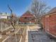 View of backyard featuring garden beds, mature tree, brick garage, and partial house view at 3921 N Raleigh St, Denver, CO 80212