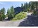 Exterior side view of a modern house surrounded by lush greenery and a winding driveway at 20600 Rangeview Dr, Morrison, CO 80465
