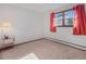 Bright bedroom with neutral carpet and views of outside through windows with red patterned curtains at 8473 Gray Fox Dr, Evergreen, CO 80439