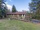 Inviting single Gathering home with a green exterior and red trim surrounded by mature trees and lush greenery at 8473 Gray Fox Dr, Evergreen, CO 80439
