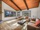 Sun-filled living room boasts hardwood floors, wooden ceiling beams, comfortable seating, and large windows at 8473 Gray Fox Dr, Evergreen, CO 80439