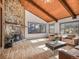 Bright living room with stone fireplace, hardwood floors, wooden ceiling, and ample natural light at 8473 Gray Fox Dr, Evergreen, CO 80439